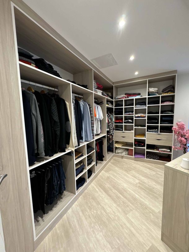 Dressing moderne avec rangements ouverts, penderies et étagères organisées.